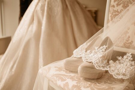 Bridal high heel shoes for happy wedding under veil on the chair.の写真素材