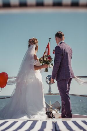 Just married couple on yacht. Happy bride and groom on their wedding day. Back view.の写真素材