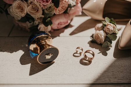 Accessories for the bride: rings, shoes, wedding bouquet and perfume. Morning bride. Wedding details. Concept and composition, forming interesting shadows from the sun.の写真素材