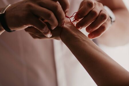 Man ties a red bracelet on woman's hand, red thread, jewelry, bracelet with a stone, women's accessories. Authentic love.の写真素材
