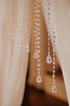 Blur Golden bokeh from beautiful crystal. Wedding arch decoration close-up. Pendants made of crystals close-up. Vertical.の写真素材