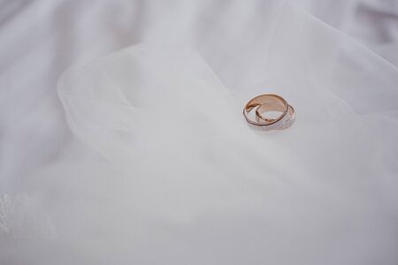 Marriage concept. Golden wedding rings on white veil. Close-up. Space for text. Top view.