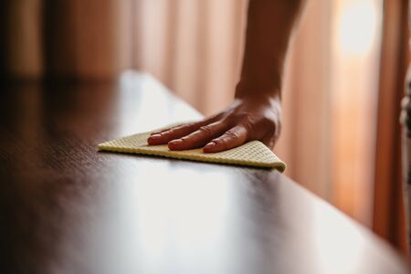 Close up woman cleaning wooden table using disinfectant blue towel. Prevent infection of Covid-19...