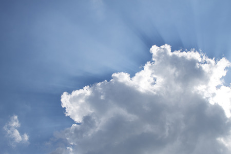 Glowing sun radiates back of  the white cloud.