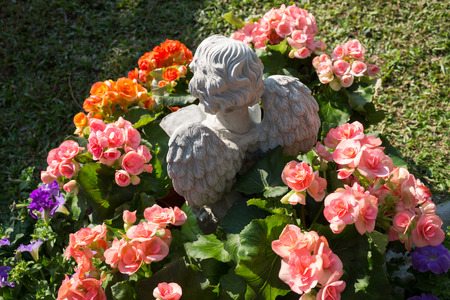 The little cupid was reading a book and surrounded by the beautiful flowers.の写真素材