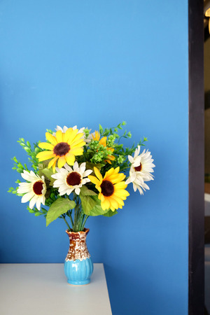 A vase of Sunflowers on the white table and blue clean background image.の写真素材