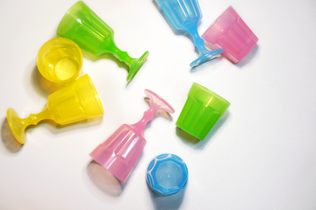 Top view: Colorful plastic glasses for kids lay on white background image, warm light effects.の写真素材
