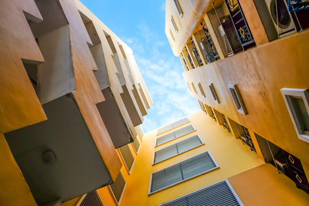 Ant's eye view yellow high rise apartment contrast with blue sky, futuristic perspective building imageの写真素材