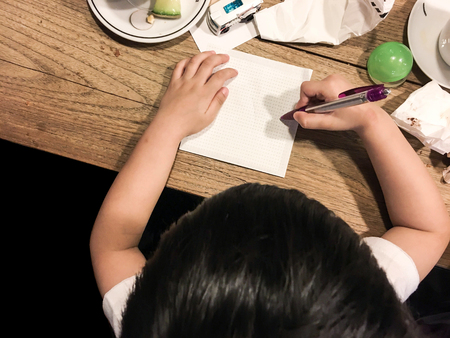 Naughty boy drawing on blank paper with very messy things on wood table, top viewの写真素材