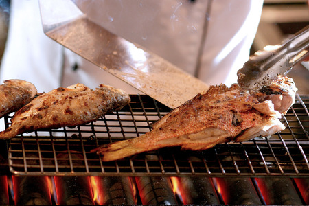 Grilled fish on the flaming grill by chefの写真素材