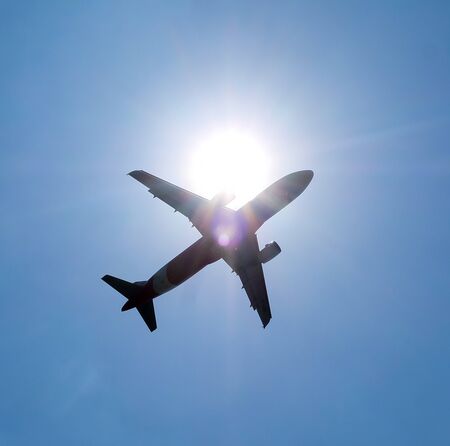 Commercial aircraft flying through the sunの写真素材