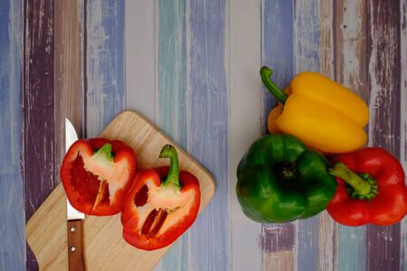 Red, green, yellow bell peppers on the wood floor