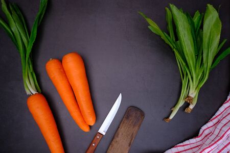 Carrots on the black wooden floor in the kitchenの写真素材