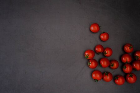 Tomatoes on the black wooden floor in the kitchenの写真素材