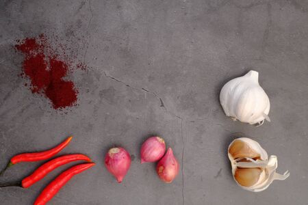 Peppers, onions, garlic and spices on the black wooden floor in the kitchenの写真素材