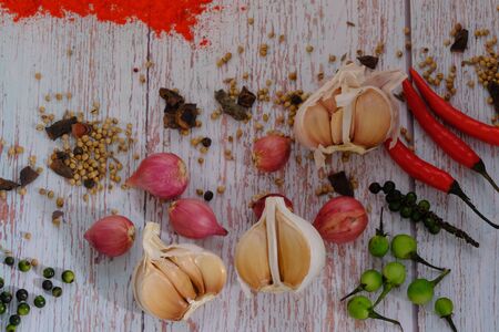 Peppers, onions, garlic and spices on the wood floor in the kitchenの写真素材