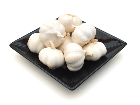 garlic in a black plate isolated on white backgroundの写真素材