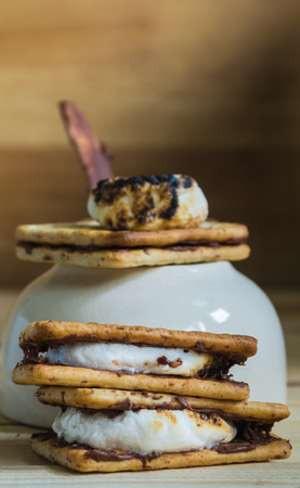 Smores and burnt marshmallow on wooden table, pan as backgroundの写真素材