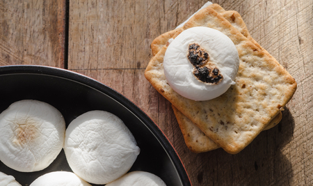 Marshmallows and piles of cracker on wooden table