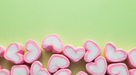 Pink heart-shaped marshmallow  on green backgroundの写真素材