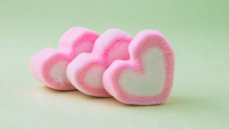Pink heart-shaped marshmallow  on green backgroundの写真素材