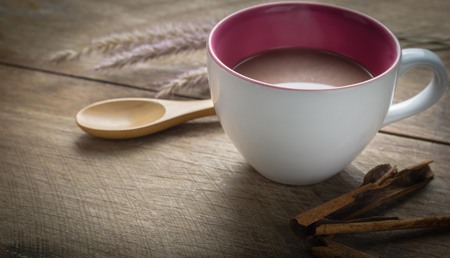 Hot chocolate cup and cinnamon sticks on wooden tableの写真素材