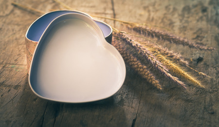 heart-shaped box with fountain grasses on a wooden board- split toning effectの写真素材