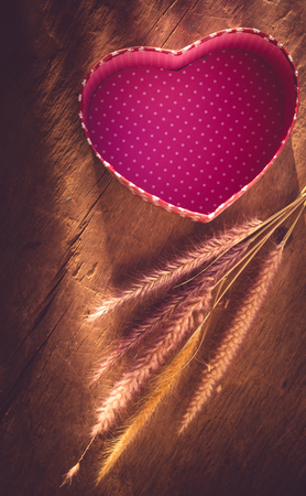 heart-shaped box with fountain grasses on a wooden board- pink color toneの写真素材
