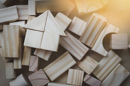 house from natural color wooden block on the stack of wooden blocks with orange light effectの写真素材