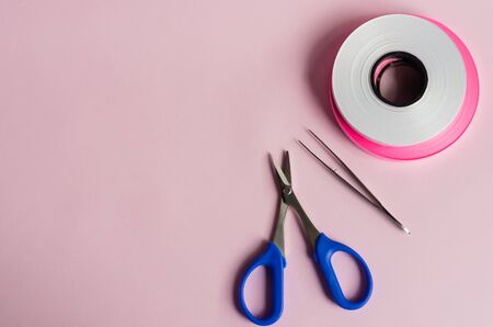 Ribbon roll on pink background with scissor and 
tweezersの写真素材