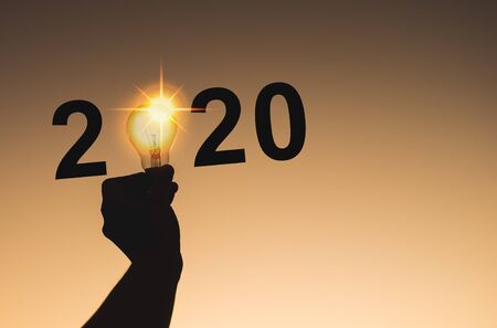 2020 New Year celebration with part of human hand holding light bulbの写真素材