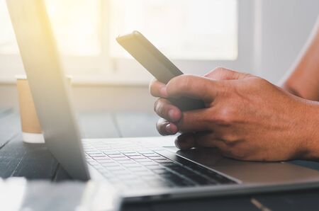 part of human hand while using smartphone at working deskの写真素材