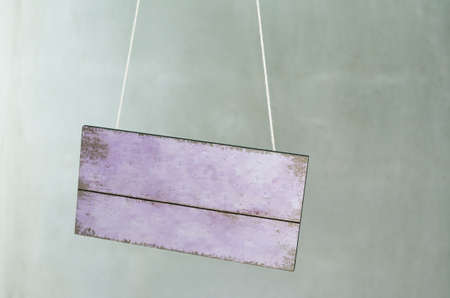 Vintage wooden signboard hang in front of concrete wallの写真素材