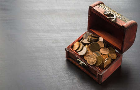 Old coins in vintage small wooden chest on black tableの写真素材