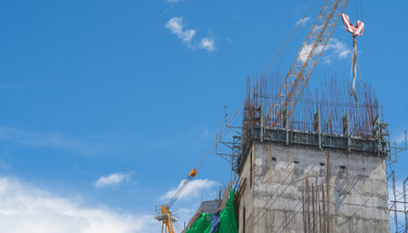 Building under construction, tower crane against blue sky backgroundの写真素材