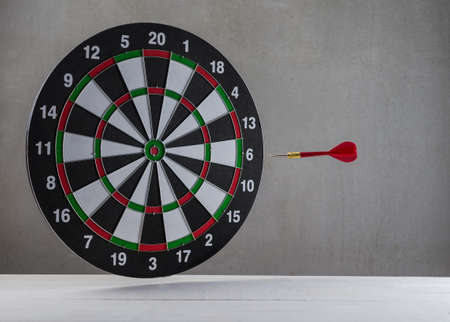floating drart arrow and dartboard over white table and grey background, business targeting concept and symbolの写真素材