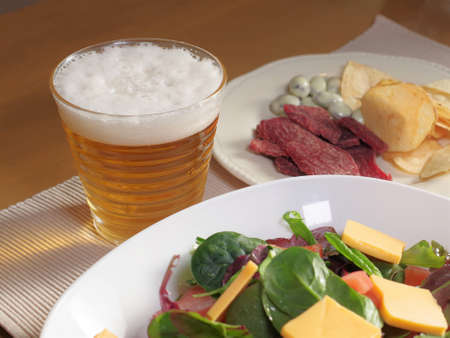 Beer poured into a glass and snacksの写真素材