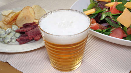 Beer poured into a glass and snacksの写真素材