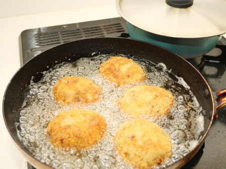 Fried potato croquettes in a frying pan on a gas stove