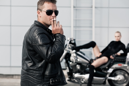 Smoking man on foreground and girl on motorcycle on background  Selective focus on manの写真素材