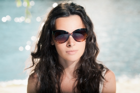 Portrait of young brunette girl in sunglasses on beachの写真素材