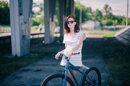 Art portrait of young redhead girl with bicycle on streetの写真素材