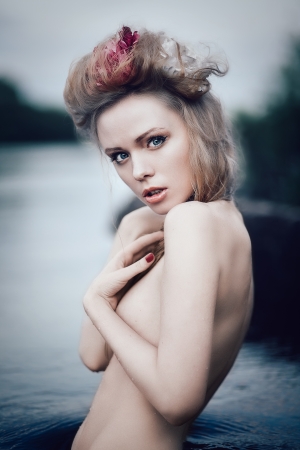 Art fashion portrait of young blond girl with flowers in hair in waterの写真素材