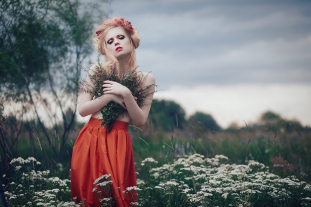 Art fashion portrait of young blond girl with flowers in hair on meadowの写真素材