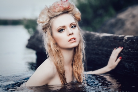 Art fashion portrait of young blond girl with flowers in hair in waterの写真素材