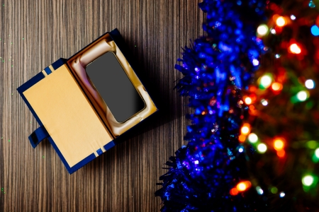 Christmas background with gift box and cell phone. Shallow depth of field