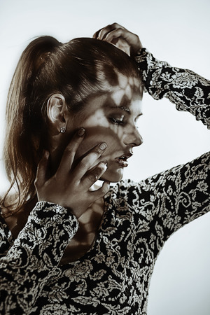 Artistic portrait of young woman, with lace shadow on faceの写真素材