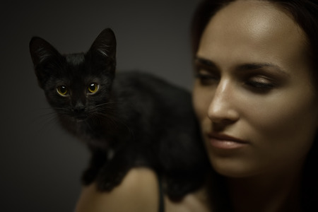 Art portrait of redhead young woman with black cat on shoulder. Shallow depth of fieldの写真素材