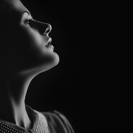 Artistic portrait of young beautiful woman on black. Copy space on rightの写真素材
