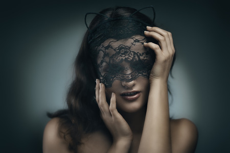 Artistic portrait of young beautiful brunette woman in lace mask. Shallow depth of fieldの写真素材